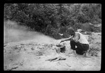 Frying fish over a campfire by George French