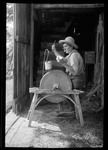 Man Sharpening Scy Blade On An Old Grinding Wheel. by George French