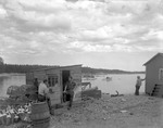 Men Near Lobster Shack Talking, Boats Behind In Harbor At Gouldsboro by George French