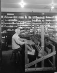 Druggist Sits At Loom In His Store While Waiting For Customers In Northeast Harbor by George French