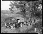 Woods Scene, Two Hunters Lift Deer Into Trailer Which Is Hooked To Jeep, Lady Behind Wheel, Another Deer Is In Trailer At Kezar Falls by George French