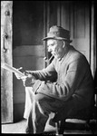 Old Timer, John, Sitting In Doorway, Smoking A Pipe And Reading by George French