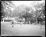 Exterior Of Main Lodge At Camp, People Playing Croquet While Others Watch by George French