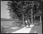 Two People Riding Horseback Along A Trail, Camps Behind, Water On Left by George French