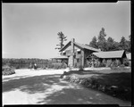 View Of Lodge From Side With Two People On Horseback On Left And Lake In Background by George French