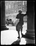 Back To View Of Newsboy In City, Leans Against Pillar Of Bld., Looks Out On Street In New Jersey by George French