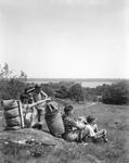 Group Of Boys With Backpacks Sitting On A Hill Overlooking A Pond In Damariscotta by French George