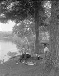 Couple On A Picnic Near A Lake, Two Fish Laying On Ground Next To Them by French George
