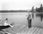 Older Man Fishing From A Dock On Lake Kezar While A Young Woman Looks On by French George