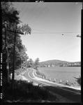 Blacktop Highway Along Shore Of Lake In Mount Vernon, Village In Distance by French George