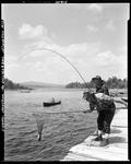 Two Men On Dock, One Netting Fish For Other At Upper Dam by French George