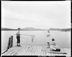 Man On Dock Netting Fish For Lady While Another Looks On At Upper Dam by French George