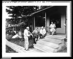 Man Showing Off Fish To Three People On Camp Porch by French George