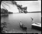 A Couple Sitting In Canoe Talking To Man Sitting On A Diving Board by George French
