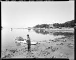 Young Boy On Shore Standing In Front Of Skiff With One Trap On It, Houses And Pier In Background At Sorrento by George French