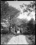 Two Women Riding Horses Down A Gravel Road In Porter by George French