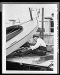 Man Sitting On A Dock Painting The Underside Of A Sailboat by George W. French