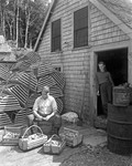 Man Shucking Clams Near A Pile Of Lobster Traps While A Girl Looks On by George French