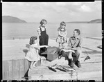 Man On A Wharf At Moosehead Talking To Three Children About A Fish He Is Holding by George French