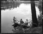 Three Ladies Sitting On A Dock At A Pond In Porter, Sharing A Pie, Nice Clouds Reflected In Water by George French