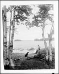 Man And His Dog Sitting On Shore Of A Lake by George French