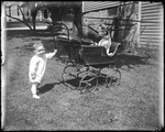 Young Child Holding Onto A Baby Carriage With A Dog In It by George French