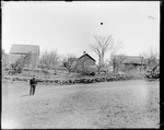 Man Standing In A Field In Front Of Stone Walls & Farm Buildings by George French