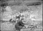 Family Outdoors Waiting For Lunch While Two Women Cook Over A Campfire by George French