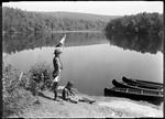 Two Boy Scouts At Lakeside With Canoes, One Sitting One With Flags Doing Semaphore by George French
