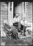 Three Men Sitting On And Around Stoop Of Rural House by George French