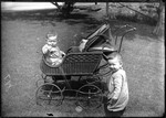 Double Exposure, Toddler Sitting In And Standing Beside A Stroller (Carriage) by George French
