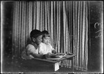 Young Boy And Girl Sitting At A Desk, Looking At A Picture Book by George French