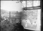 Split Shot, Woman In A Field And Man Photgraphing A Woman Holding A Cat Under A Tree by George French