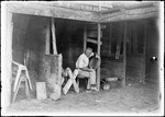 Man In A Barn Sitting On A Stool Looking At A Basket by George French