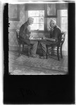 Two Older Men Sitting Playing Checkers By A Window by George French