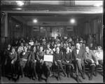 Many Young Men (Boys) Gathered Together In A Room Grouped With Signs Bearing Native American Tribe Names by George French